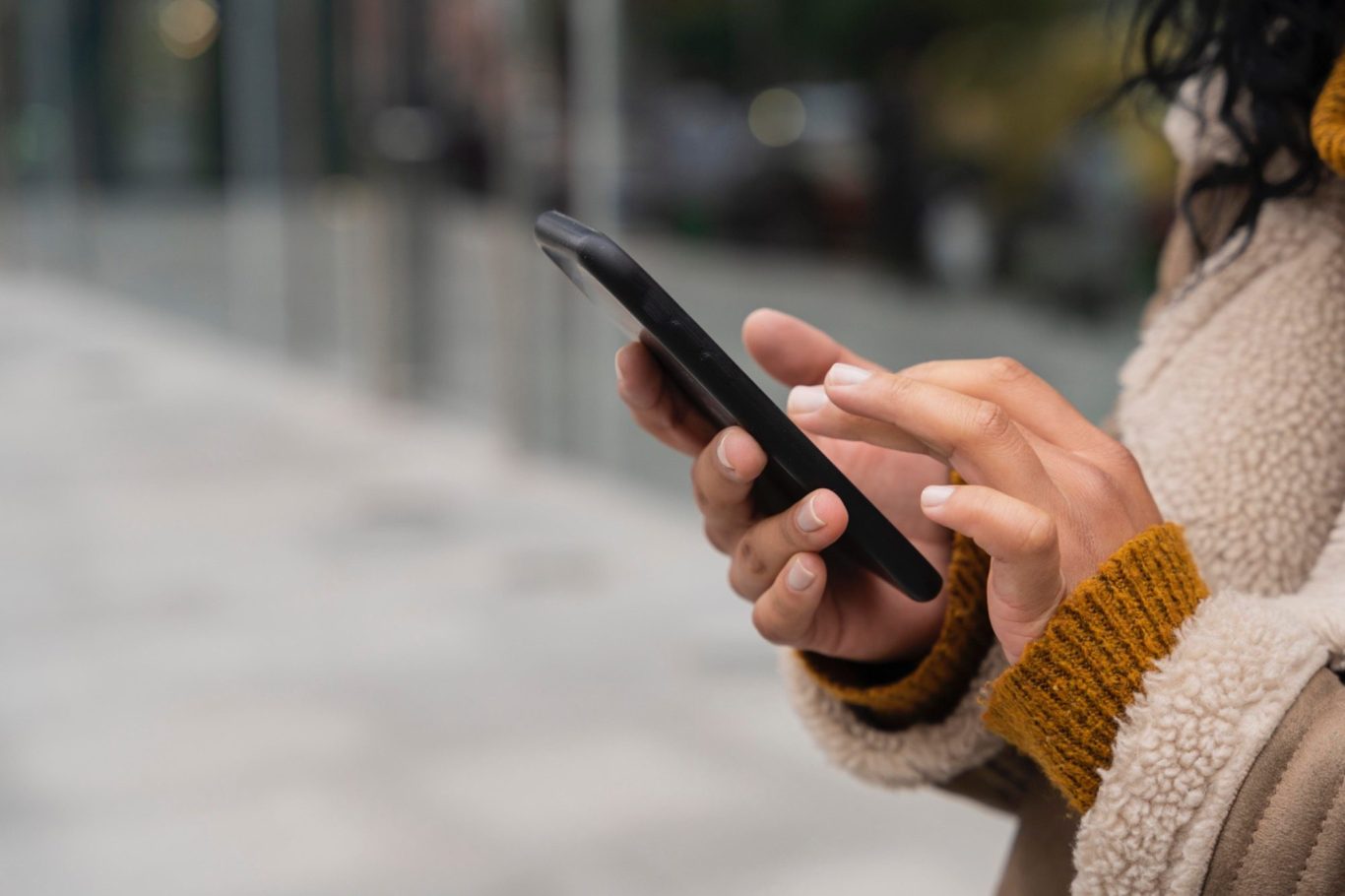 Paarberatung, Eheberatung, Einzelberatung Frankfurt Eine Person hält ein Smartphone und tippt darauf, mit einer neutralen Umgebung im Hintergrund.